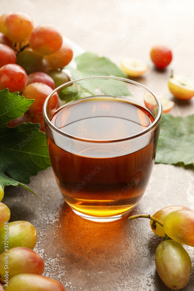 Glass of juice and plate with grape on gray background Glass of juice and plate with grape on gray background