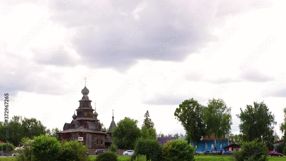 An ancient wooden temple in dense greenery. There are small wooden houses nearby. Thick clouds slowly float across the sky. An ancient wooden temple in dense greenery. There are small wooden houses nearby. Thick clouds slowly float across the sky.