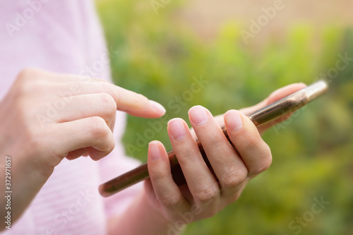 Side view of woman using mobile phone outdoor against green background