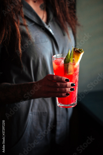 Woman holding red cocktail in a highball
