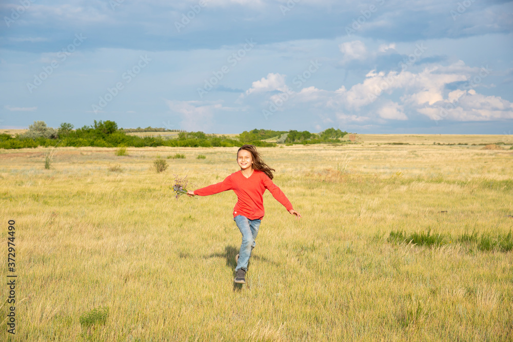 A girl with long hair runs towards the field in the summer. A girl with long hair runs towards the field in the summer.
