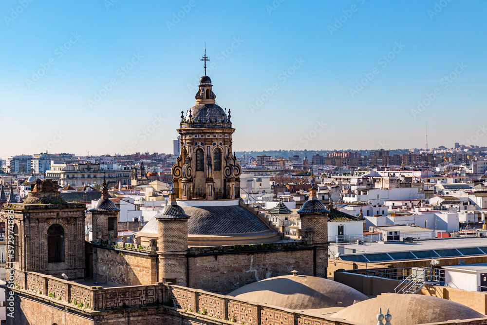 Cityscape with the roof and one of the tower of the Cathedral of Saint Mary of the See, sunny day with a clear blue sky in Seville, Spain