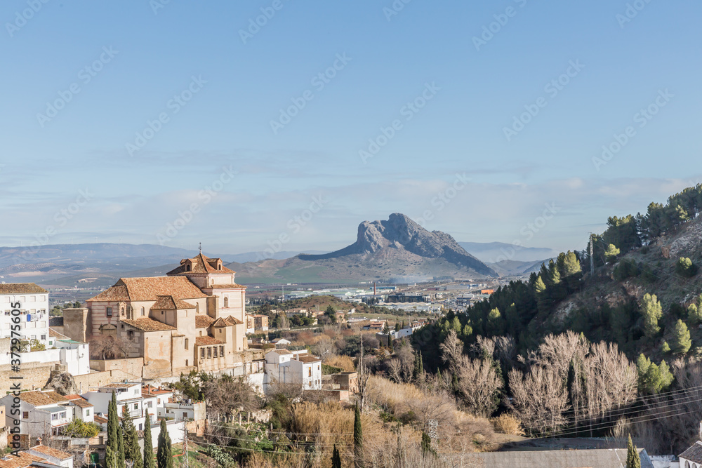 Partial urban landscape of the city of Antequera, a hill with arid vegetation with the Peña de los Enamorados or The Lovers' Rock in the background, sunny day in the province of Malaga, Spain