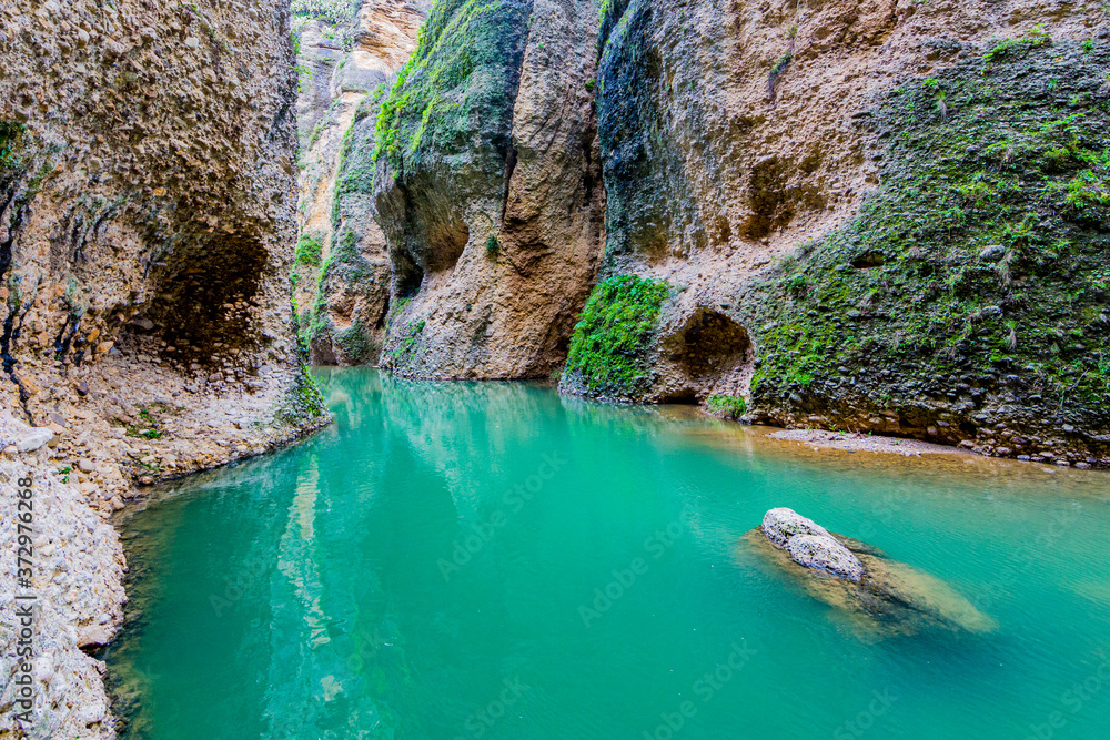 Rocky slopes with green moss of the the canyon or Tajo de Ronda and the Guadalevin river with its turquoise waters, wonderful day in the province of Malaga, Spain Rocky slopes with green moss of the the canyon or Tajo de Ronda and the Guadalevin river with its turquoise waters, wonderful day in the province of Malaga, Spain