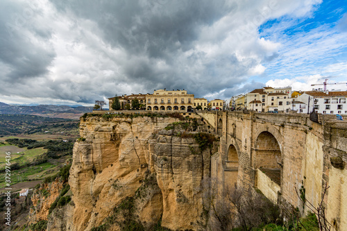Ronda city on the mountain plateau, the Tajo de Ronda and the New Bridge (Puente Nuevo) with the valley in the background, cloudy day with abundant clouds in the province of Malaga Spain