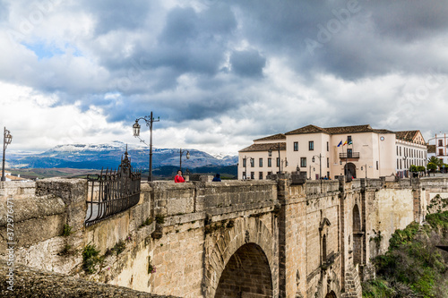New Bridge, (Puente Nuevo) a part of the city of Ronda and snowy mountains in the background, wonderful day with abundant gray clouds in the province of Malaga Spain