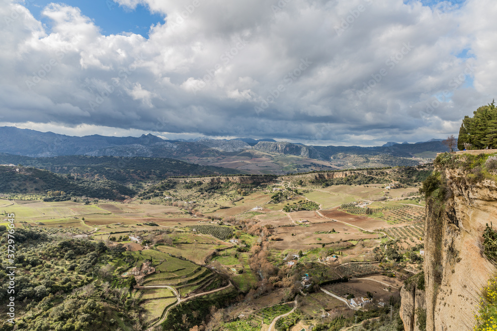 Panoramic view of the valley of Ronda with farmland and mountains in the background, sunny day and the abundant gray clouds in the province of Malaga, Spain