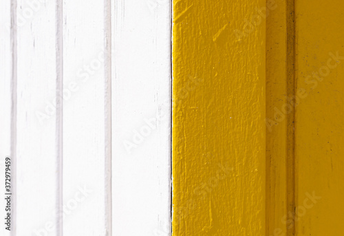 Corner detail of a white and yellow wooden shed illuminated by morning light in summer