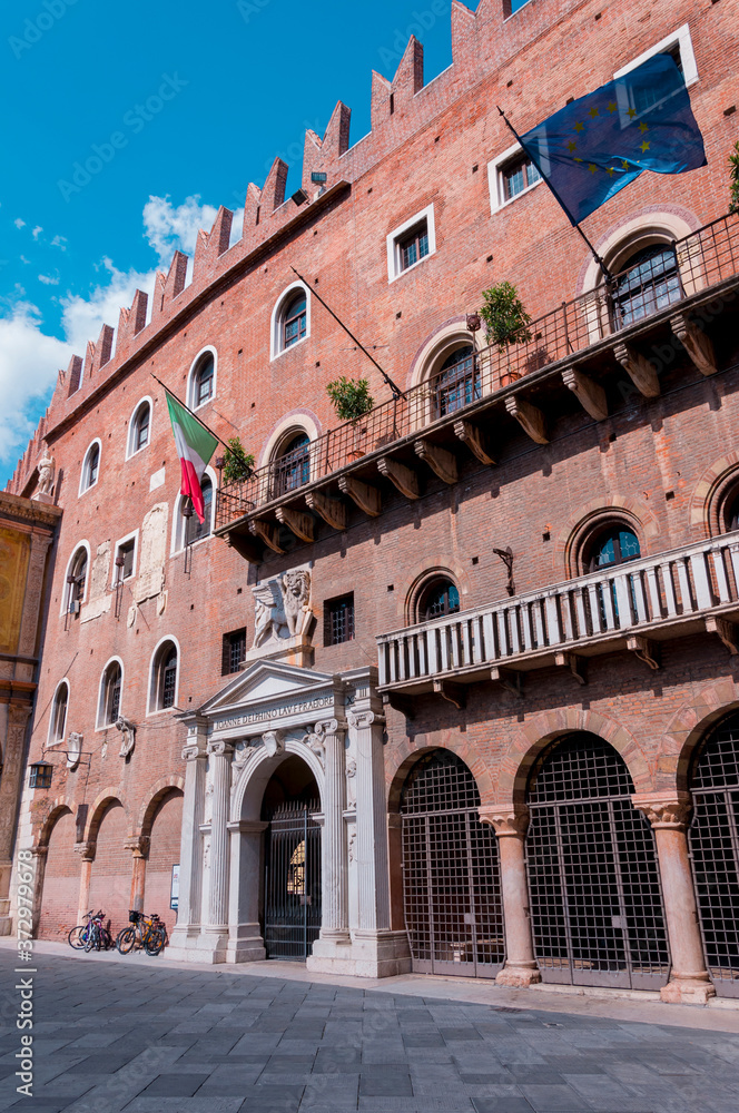 Red Brick Palace of Cansignorio with Italian and European Union Flags at Piazza dei Signori located in Verona, Italy.