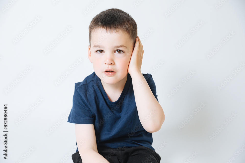 little boy on a white background holds a hand to his ear little boy on a white background holds a hand to his ear