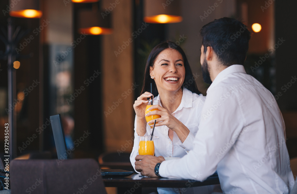 The couple is sitting at a table in a pub, drinking orange juice, talking