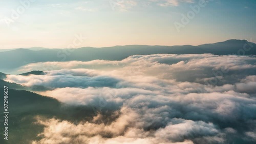 Time lapse with sunrise, low clouds and fast moving morning mists over the tree-covered mountain slopes, the Rhodopes in Bulgaria