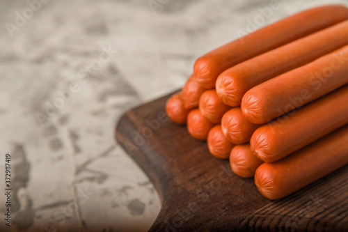 Raw sausages on a wooden board close-up and copy space. Boiled sausages for cooking.