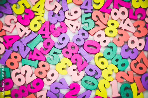Bright multicolored background of wooden numbers from zero to nine. Top view  abstract texture with numbers. White bar in the center for inserting text. Concept  back to school  math.