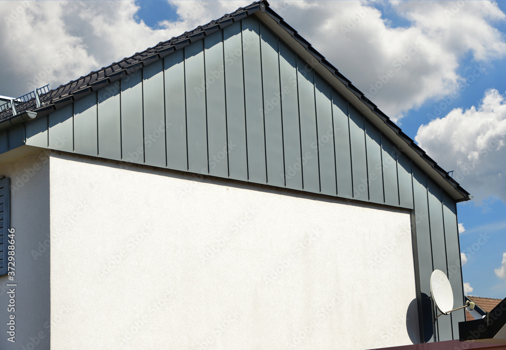 Obraz premium Stehfalz-Metall-Fassadenverkleidung des Dachgeschosses an einem modernen Einfamilienhaus