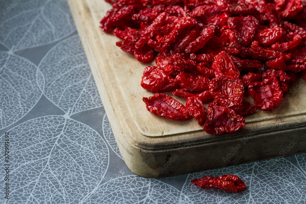 Close-up sun-dried tomatoes with spices and olive oil on wooden cutting board, background or concept, selective focus Close-up sun-dried tomatoes with spices and olive oil on wooden cutting board, background or concept, selective focus