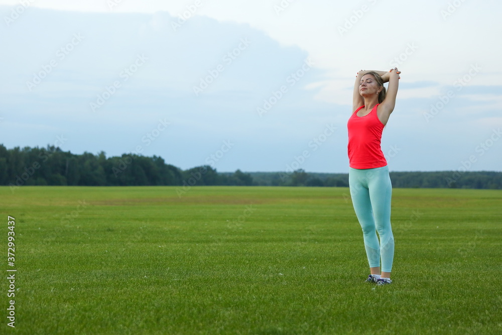sport woman is doing yoga exercises on large grass field on sunset. sport woman is doing yoga exercises on large grass field on sunset.