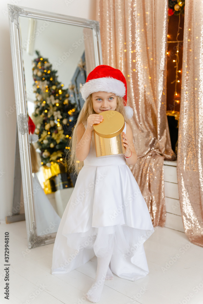 Little cute girl in Santa hat opens a Christmas present. Little cute girl in Santa hat opens a Christmas present.