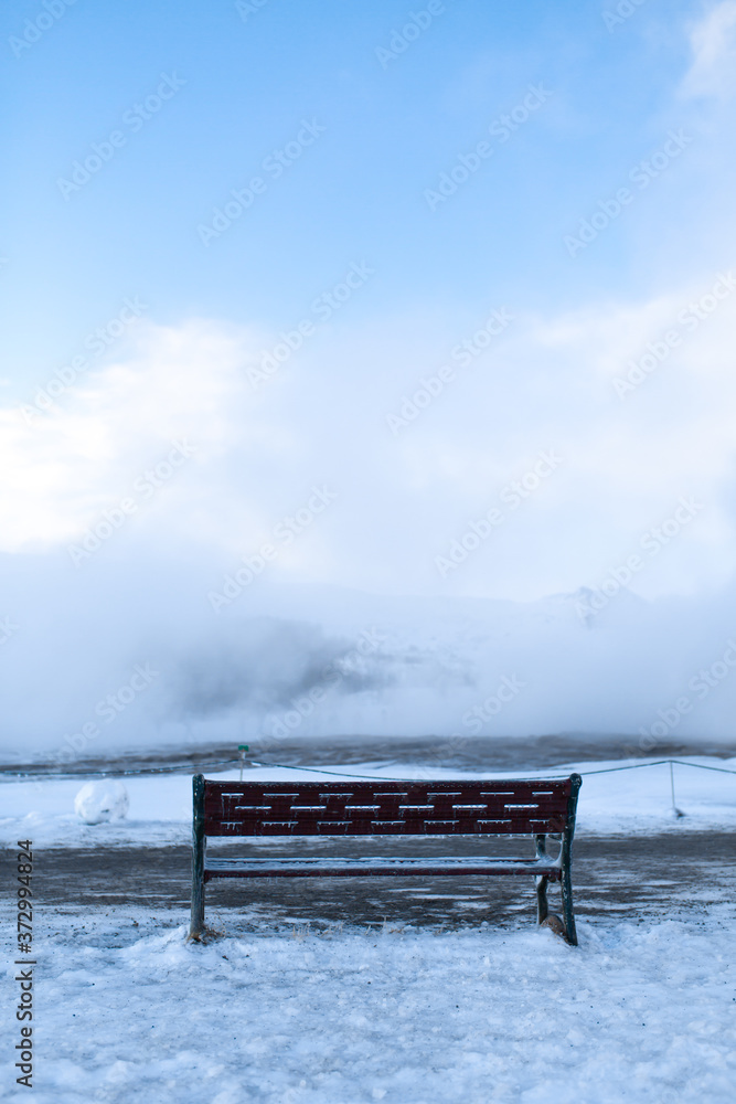 Bench for rest overlooking a cloud of steam in winter