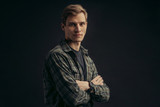 portrait of young attractive caucasian boy in checkered shirt looking at camera isolated over black background. posing at camera, studio portrait
