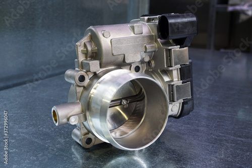 Photos New throttle valve of a modern car engine on a steel background