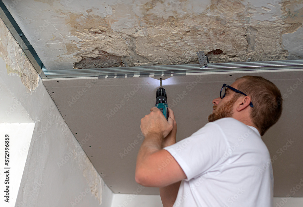 Construction worker assemble a suspended ceiling with drywall an. D