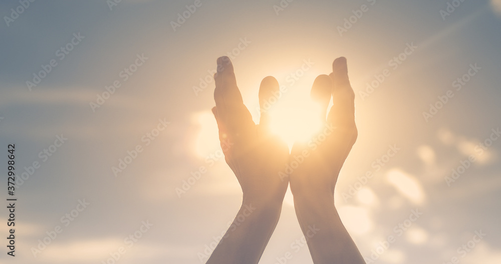 hands in the sky holding the sun. Spiritual healing concept. 