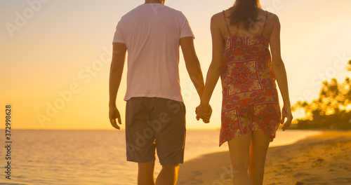 couple walking on tropical beach holding hands. 