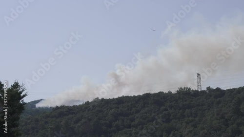 Firefighting airplane fly over a forest fire on a sunny day photo