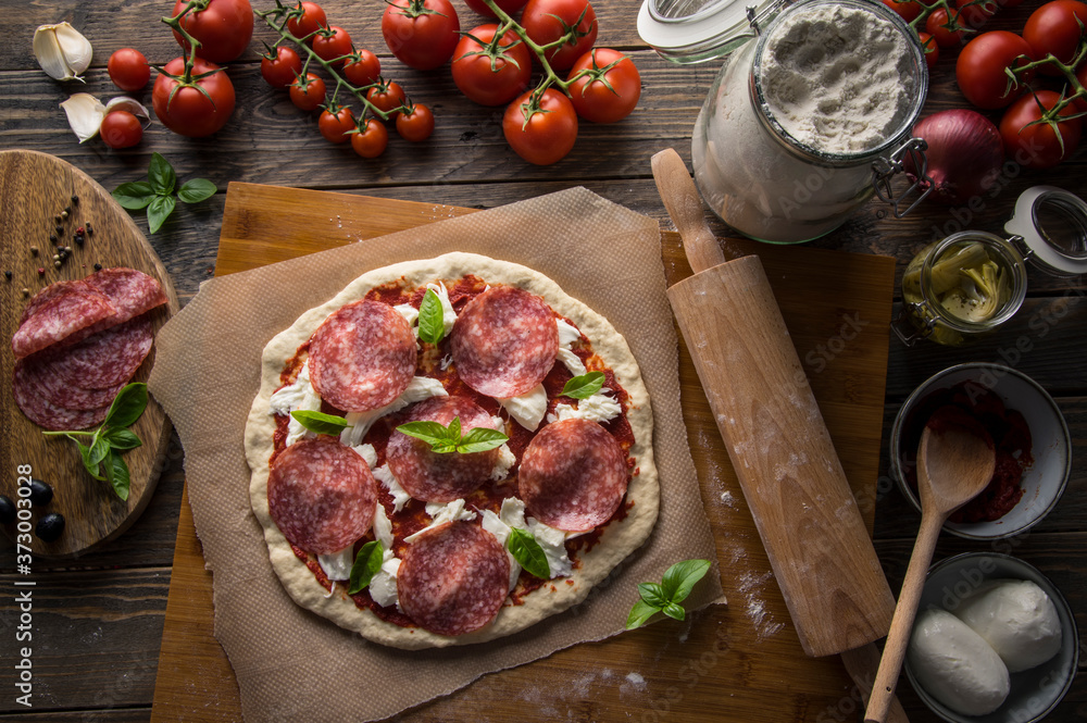 A woman preparing a pizza, knead the dough and puts ingredients on kitchen table. A woman preparing a pizza, knead the dough and puts ingredients on kitchen table.