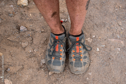 Dirty hiking shoes on a hiker, standing with feet together.