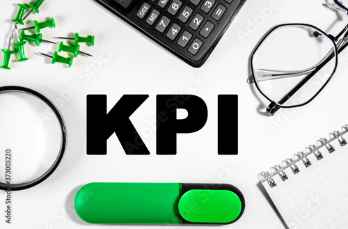 Business concept. On the wooden table is a calculator, magnifer, green markers, glasses, pins and a notebook with the inscription KPI- Business Coaching photo