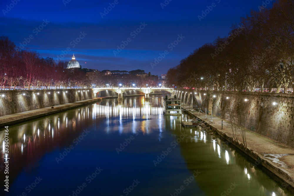 Foto noturna de longa exposição da ponte iluminada sobre o rio na cidade de Roma.