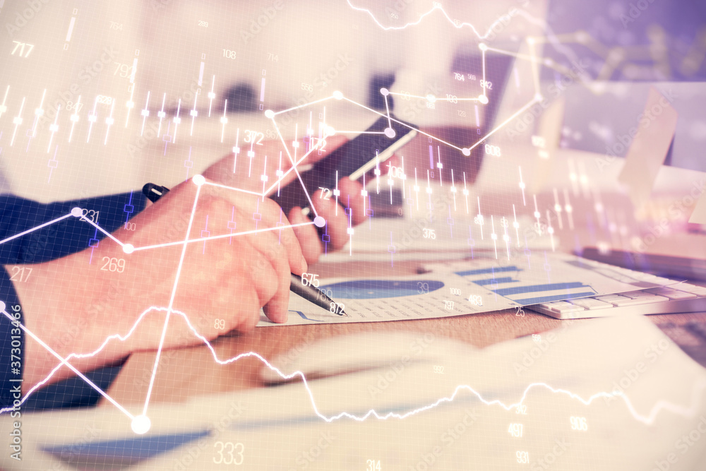 Double exposure of man's hands holding and using a phone and financial graph drawing. Analysis concept. Double exposure of man's hands holding and using a phone and financial graph drawing. Analysis concept.