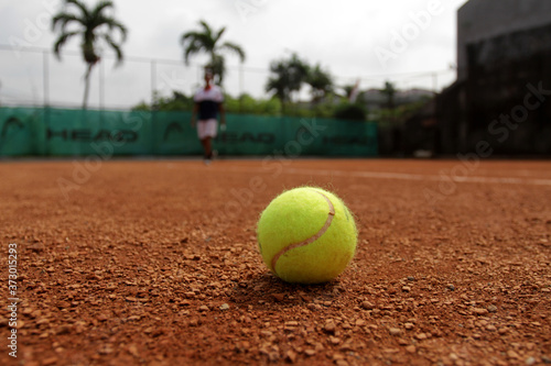 Close up of tennis ball on clay court. Tennis ball on a clay court. Red clay tennis court. Sand on a tennis court