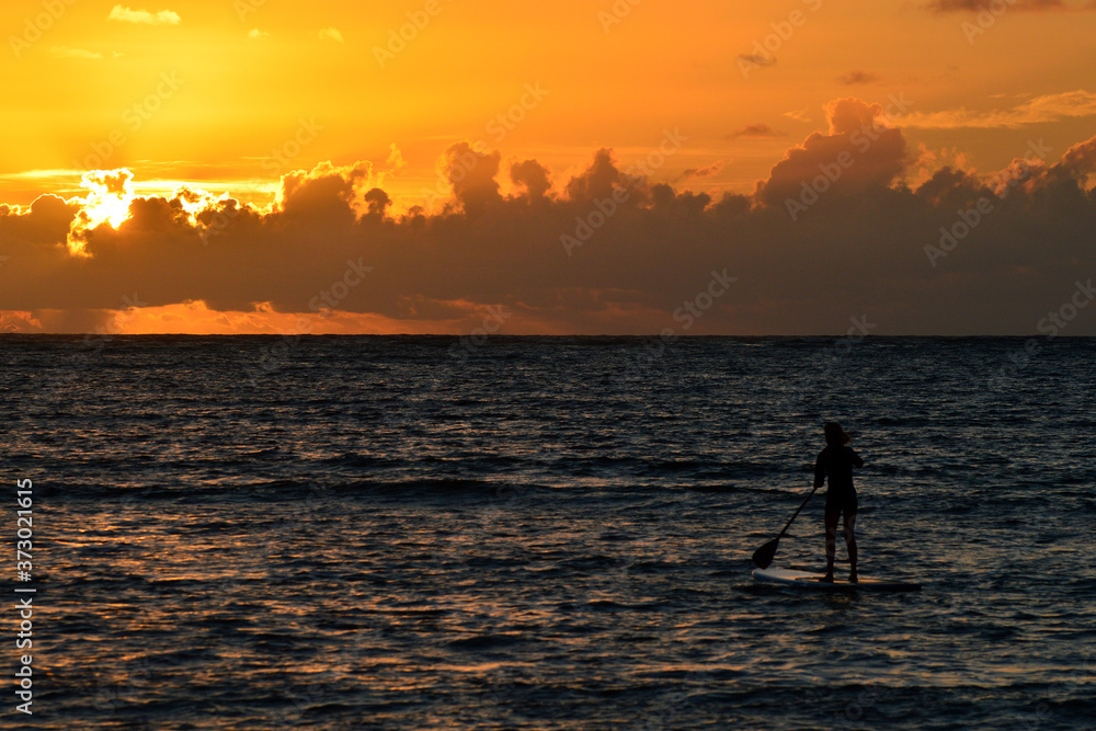 A paddle boarder goes out to greet the sunrise