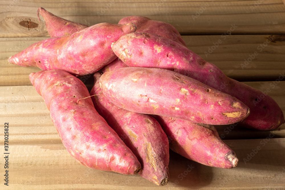 Red sweet potato pile on wooden background in Brazil Red sweet potato pile on wooden background in Brazil