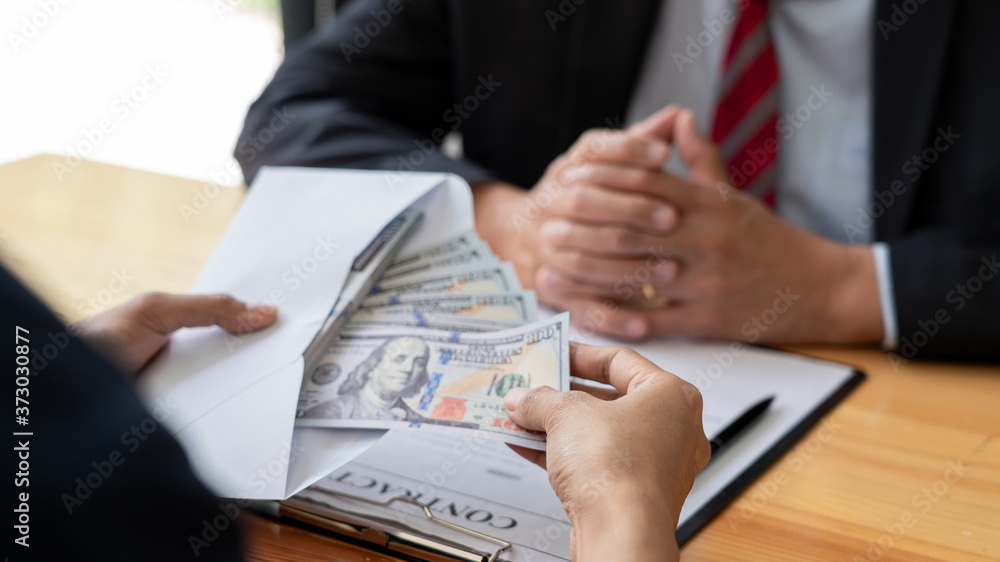 Φωτογραφία Businessman reciving money United States Dollars bills to corruption from his partner in business at working desk - bribery concept