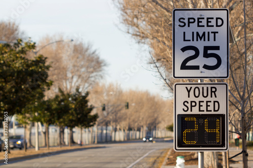 25 mph speed limit sign and radar speed indicator sign on a street. photo