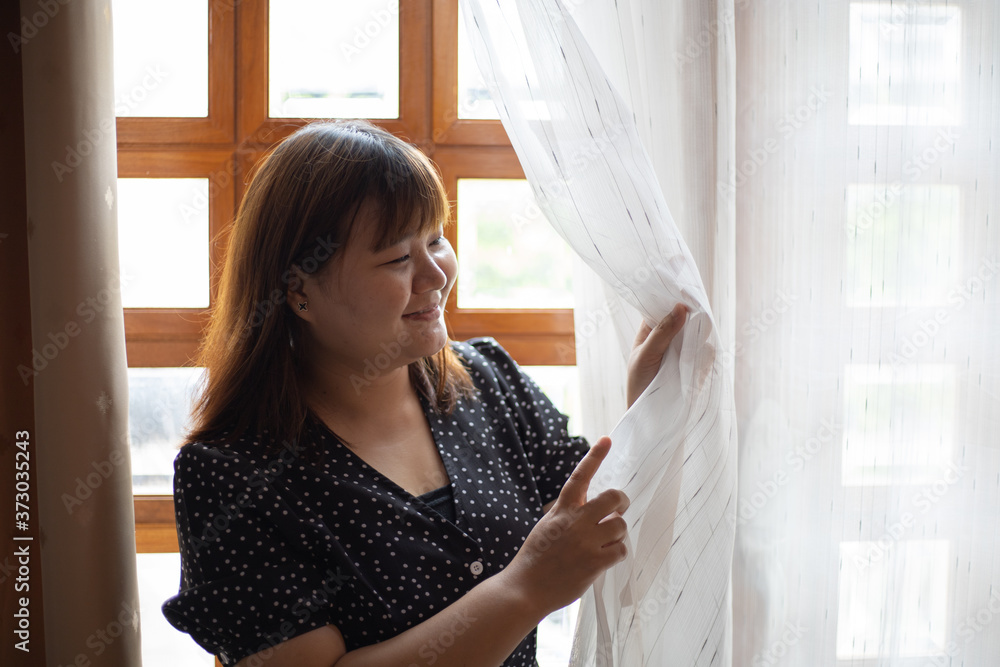 Portrait of a chubby woman looking outdoors through a window at home or hotel room. Portrait of a chubby woman looking outdoors through a window at home or hotel room.