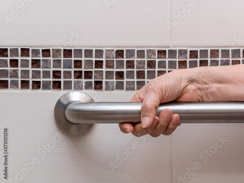 hand of elderly woman holding aluminium rail in toilet. Close up view. photo