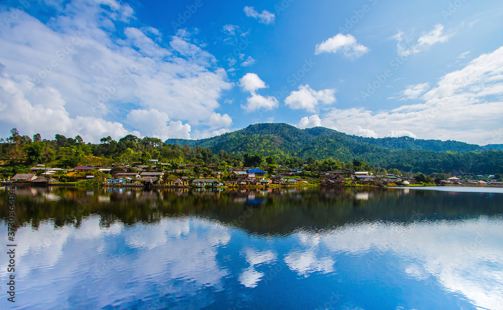 The village next to the river. The backdrop has mountains and beautiful blue turquoise sky. The river has a beautiful reflection. Village in Pai, Mae Hong Son, Thailand