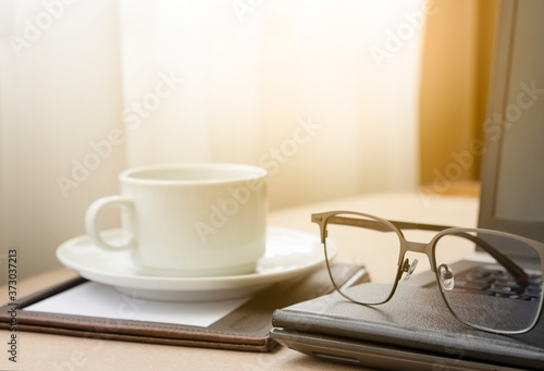 Working from home with laptop glasses pen and coffee cup hot in the morning. Workspace background composition with space for text. Enjoy love relax time during working at home with copy space.