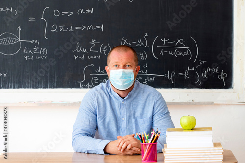 Male teacher in the classroom wearing mask. Learning during coronavirus pandemic concept.