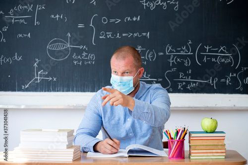 Male teacher in the classroom wearing mask. Learning during coronavirus pandemic concept.