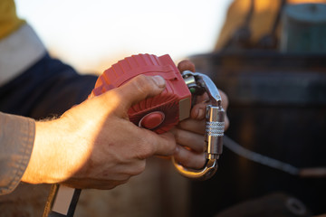 Auditor inspector hand holding inspecting an inertia reel shock absorbing fall arrest fall restraint protection device equipment ensure is working correctly as safety daily inspection prior used 