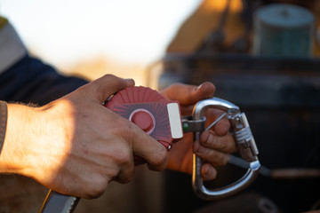 Auditor inspector hand holding inspecting an inertia reel shock absorbing fall arrest fall restraint protection device equipment ensure is working correctly as safety daily inspection prior used 