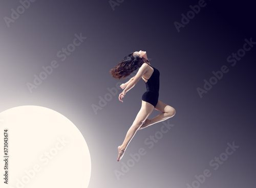 Obraz na plátně A long-legged girl jumping in front of a minimalist, graceful background