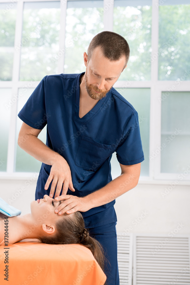 Bearded osteopath healing eyes of woman Bearded osteopath healing eyes of woman
