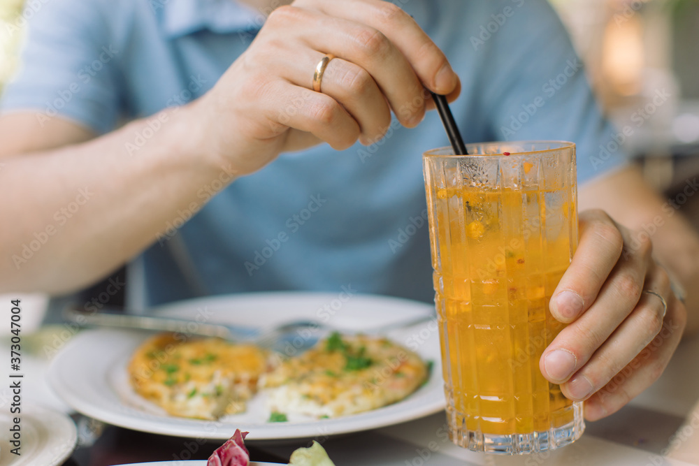 Man drinking non-alcoholic refreshing lemonade on summer terrace. Close up. Man drinking non-alcoholic refreshing lemonade on summer terrace. Close up.